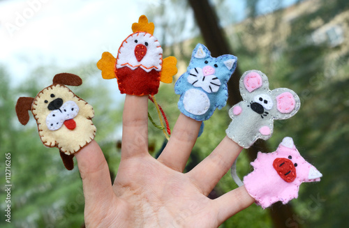 Hand wearing 5 finger puppets: dog, cock, cat, mouse, pig