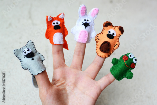 Hand wearing 5 finger puppets; wolf, fox, rabbit, bear, frog photo