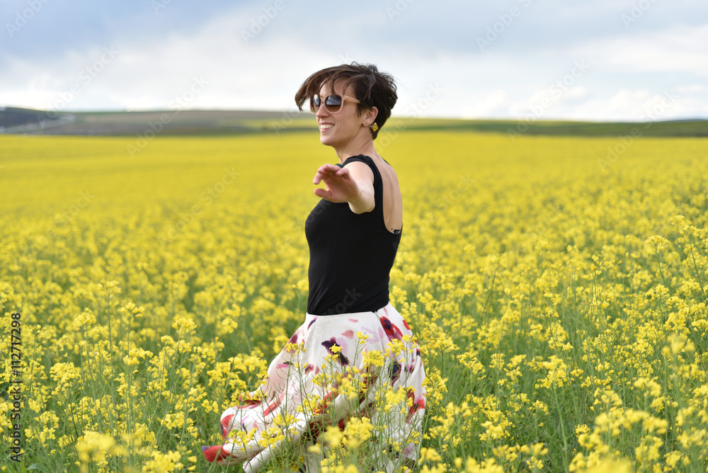 Fototapeta premium Happy woman cheering in canola field in the summer