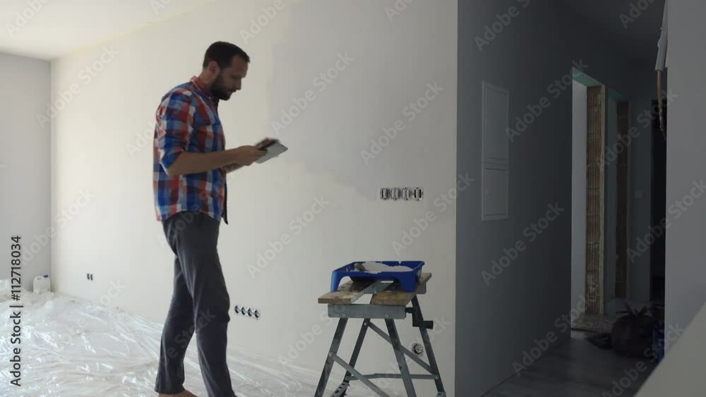 Young man painting wall and using tablet at his new home
Young man painting wall and using tablet at his new home