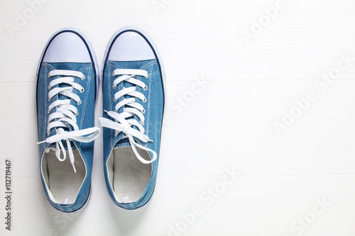 Youth classic gumshoes with white the laces on wooden background