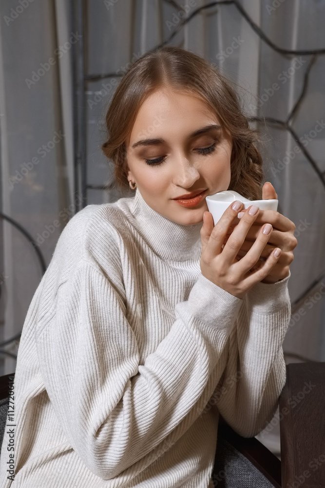 pretty girl in sweater and socks sitting behind the table wit cup pretty girl in sweater and socks sitting behind the table wit cup