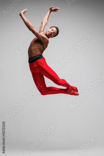 Young and stylish modern ballet dancer on gray background