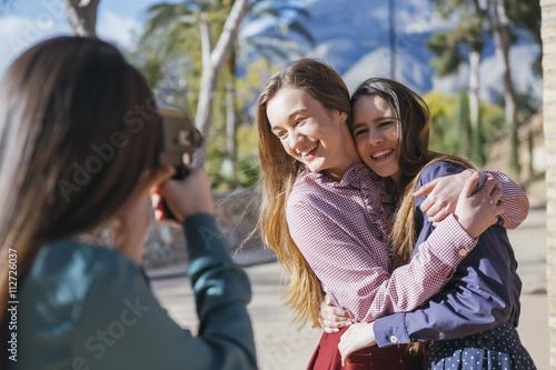 Two smiling women posing to female photographer