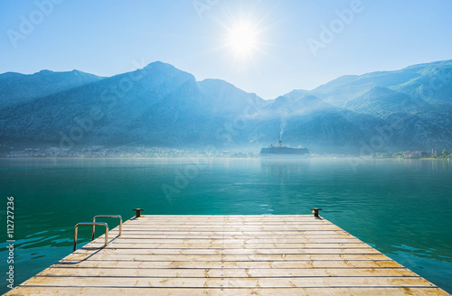 Early misty morning on the pier with sea, Kotor city and mountain views. Kotor bay. Montenegro
