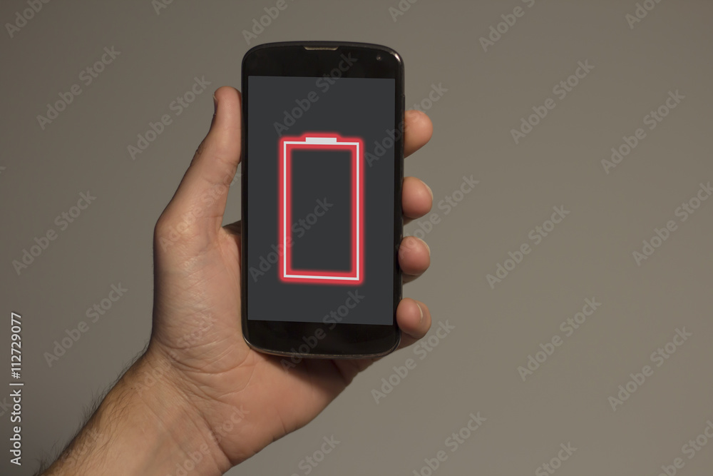  Hand holding smartphone with low battery alert on the screen