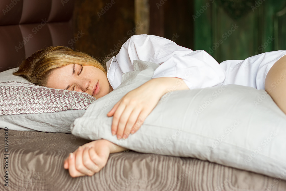 girl sleeps on the bed in white men's shirt