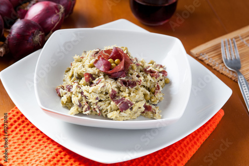 Risotto con bresaola e piselli nel piatto di ceramica bianca sulla tavola apparecchiata photo