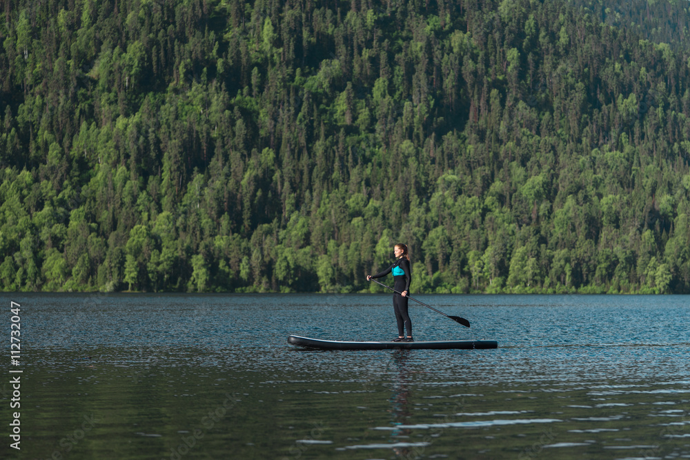 Smiling woman paddleboarding on the mountain lake Smiling woman paddleboarding on the mountain lake