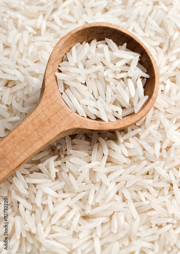 Raw rice in wooden spoon.  Close up, high resolution product.