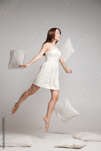 Photography Woman in white dress in mid air with flying pillows