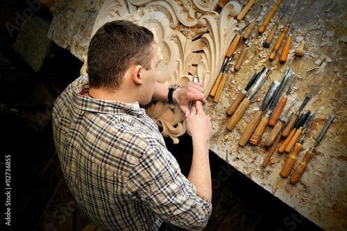 Photos carving with chisel ornamental objects in workshop