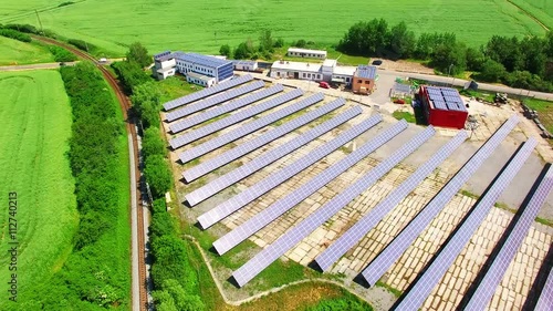 Camera flight over a solar power plant in agricultural landscape. Industrial background on renewable resources theme. Industry of power and fuel generation in European Union. photo