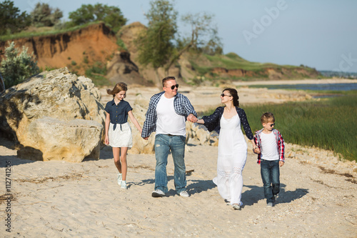 Family walking on the beach, girl, boy, the parents. Sunset, happiness, tourism, leisure, family vacation, sunlight.
