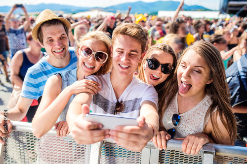 Teenagers at summer music festival in crowd taking selfie photo