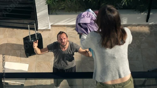 Couple fighting, woman throwing out her husband clothes from terrace, super slow motion 240fps

