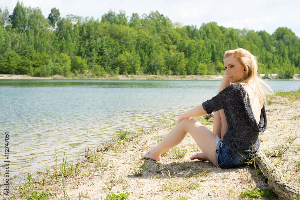 Summer / pretty woman sitting in front of a lake Summer / pretty woman sitting in front of a lake