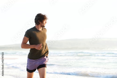 Handsome young man running by the ocean