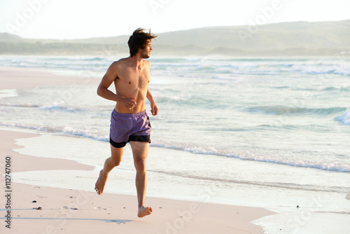 Attractive man running shirtless at the beach