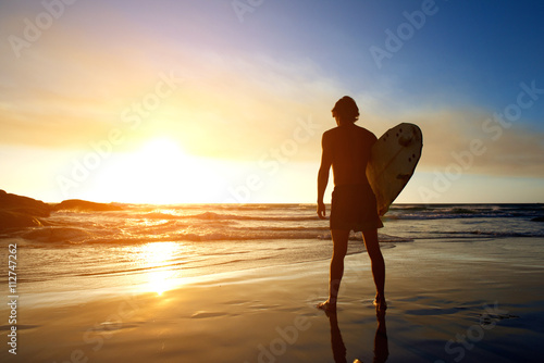 Surfer watching sunset on the beach