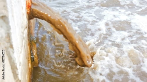 Mad water pouring from draiage into river.