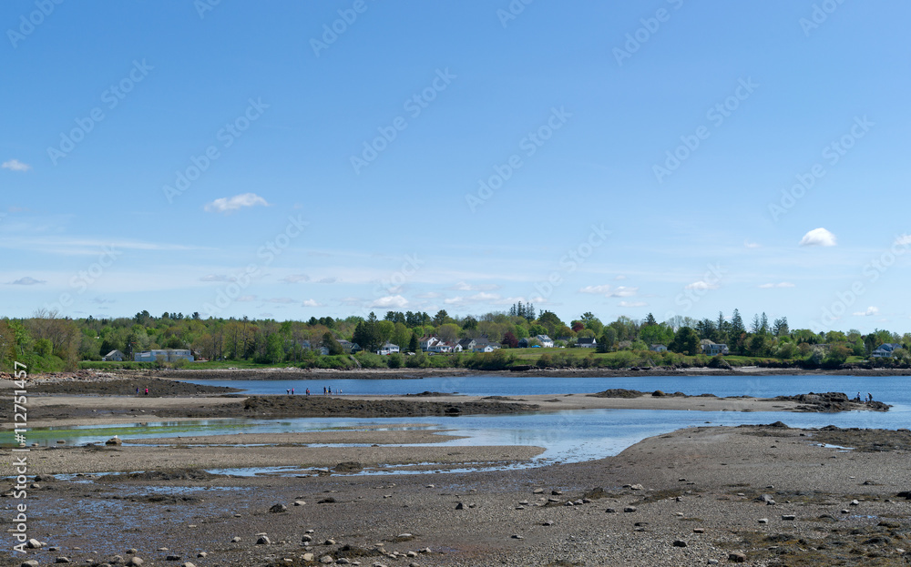 Low tide at Searsport Maine with a sand peninsula and distant people exploring the seashore.