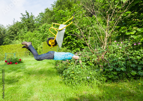 Man flies with wheelbarrow in a bush. photo