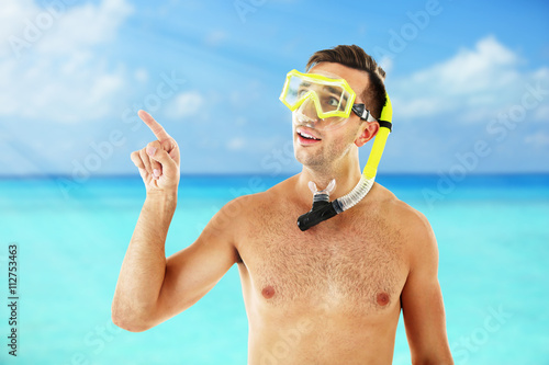 Young man with swimming mask or goggles on blurred sea background