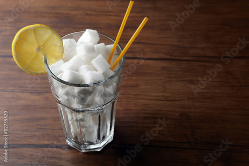 Highball glass with lump sugar on wooden table