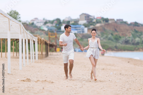 Barefoot couple on sand seashore in cloudy day
