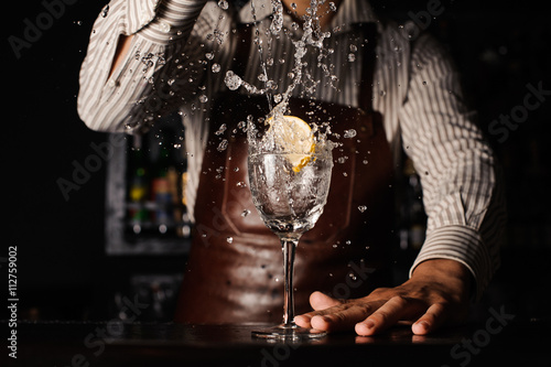splash in a glass with lemon barman on background photo
