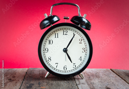 Retro alarm clock with five o'clock and five minute on white background .Retro Clock with red background. Black retro alarm.Clock concept. Retro Clock. Black clock. Clock alarm at five o'clock.