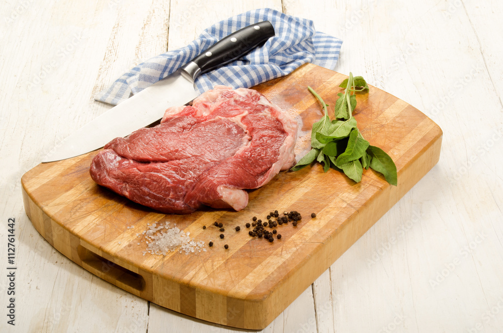 raw beef shoulder on wooden board with sage