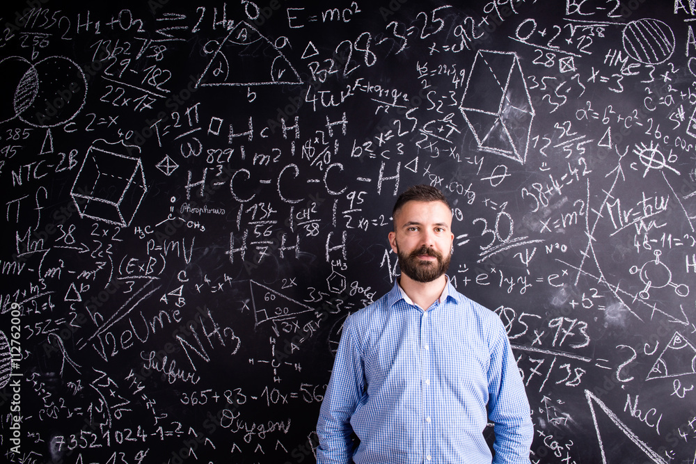 Hipster teacher against big blackboard with mathematical symbols Hipster teacher against big blackboard with mathematical symbols