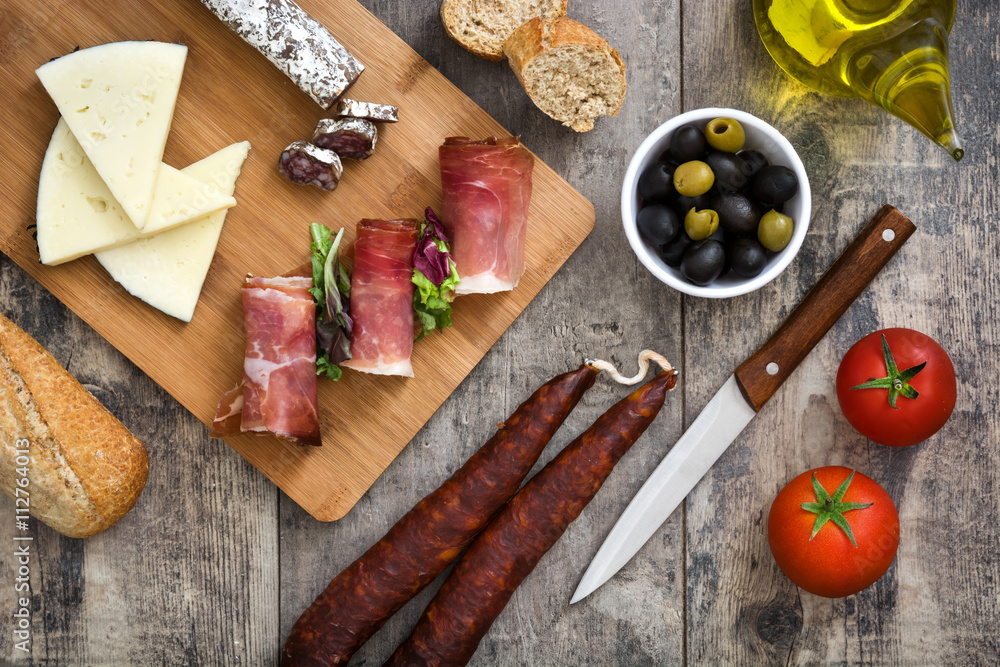 Spanish serrano ham, cheese and sausage on a rustic wooden background
Spanish serrano ham, cheese and sausage on a rustic wooden background