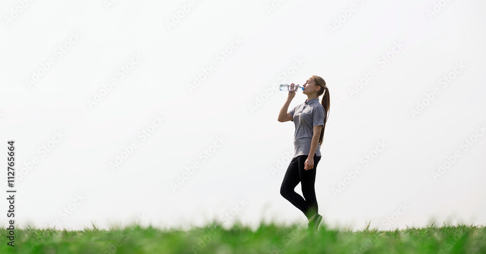 Woman drinking natural water in green field. Concept of health, thirst, hot weather.