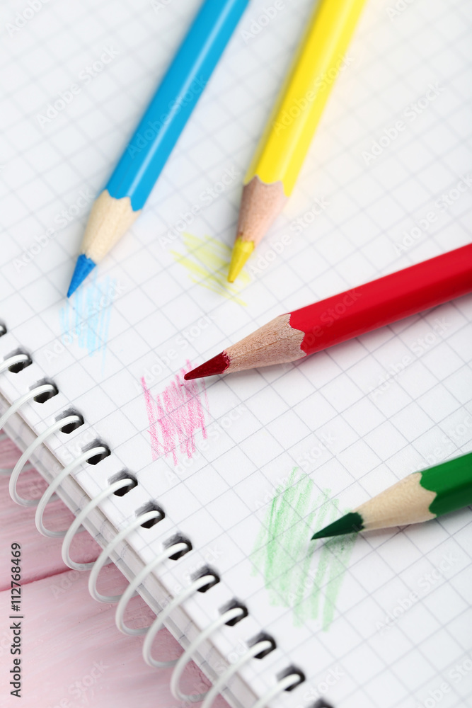 Drawing colourful pencils with notebook on a wooden background Drawing colourful pencils with notebook on a wooden background