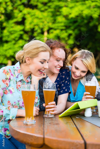Woman showing friends touch pad in beer garden