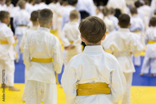Children in kimono sitting on tatami on martial arts seminar. Selective focus on a boy