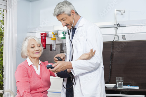 Doctor Checking Blood Pressure Of Senior Woman In Rehab Center