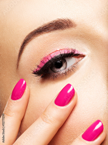 Closeup woman face with pink nails near eyes.