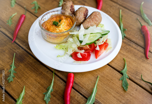 Delicious grilled beef meatball served on a white plate with tomato and lettuce