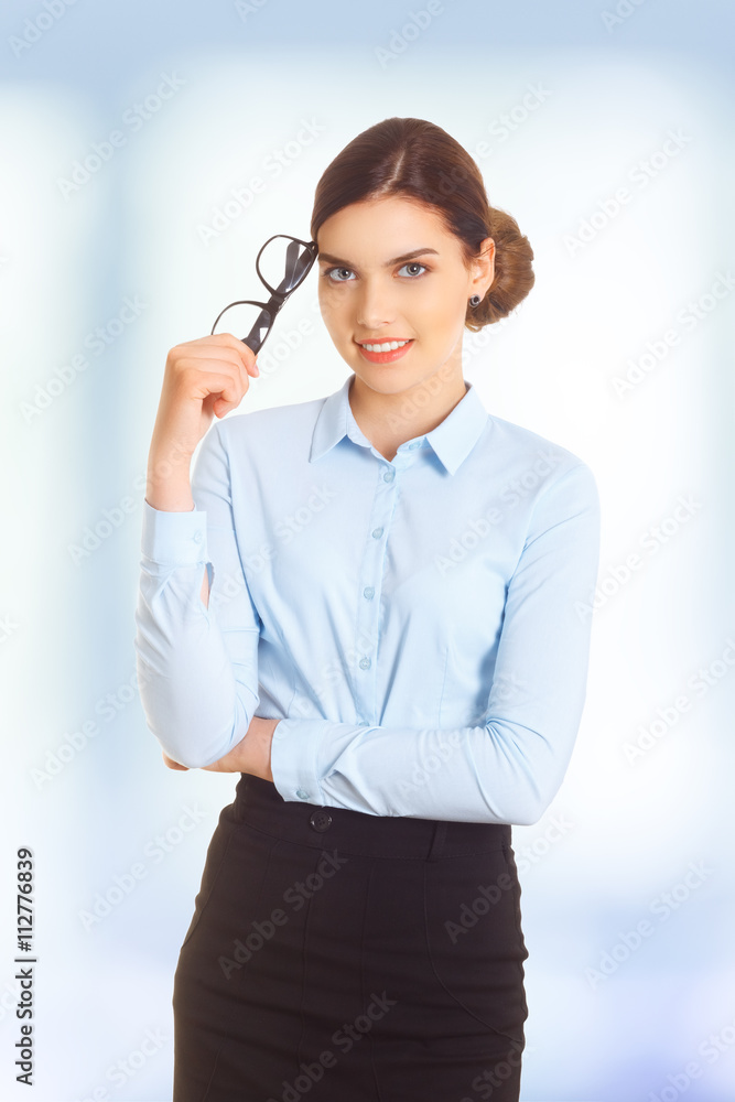 Portrait of happy smiling young cheerful businesswoman in blue clothing, with glasses in crossed arms pose. Portrait of happy smiling young cheerful businesswoman in blue clothing, with glasses in crossed arms pose.