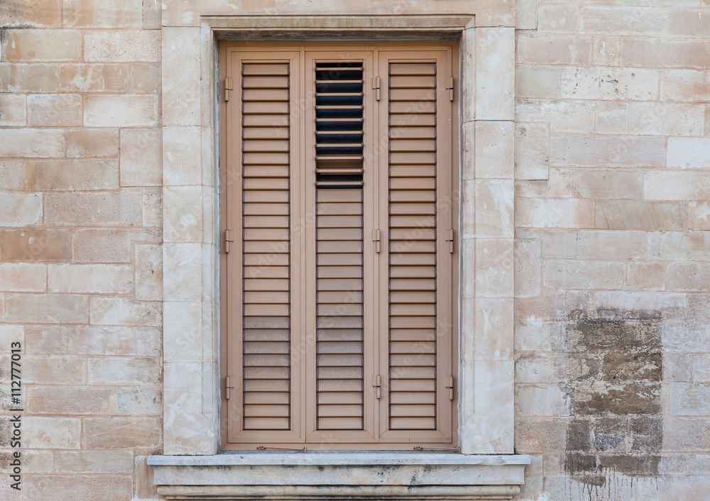 Fototapeta premium Closed beige window on light wall