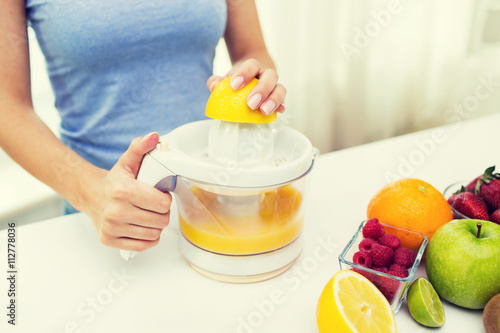 close up of woman squeezing fruit juice at home