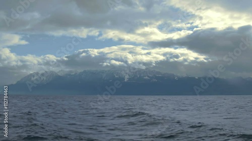 Stormy weather in Swiss Alps, thick clouds covering sky, lake waves splashing