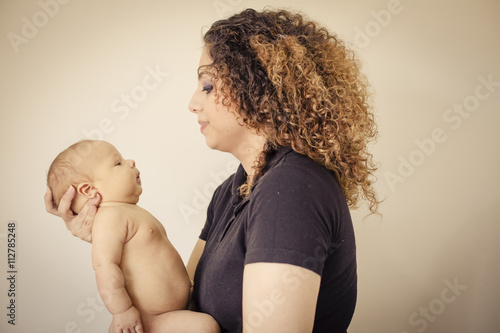 Brunette Mom playing with her newborn baby isloated on off white background