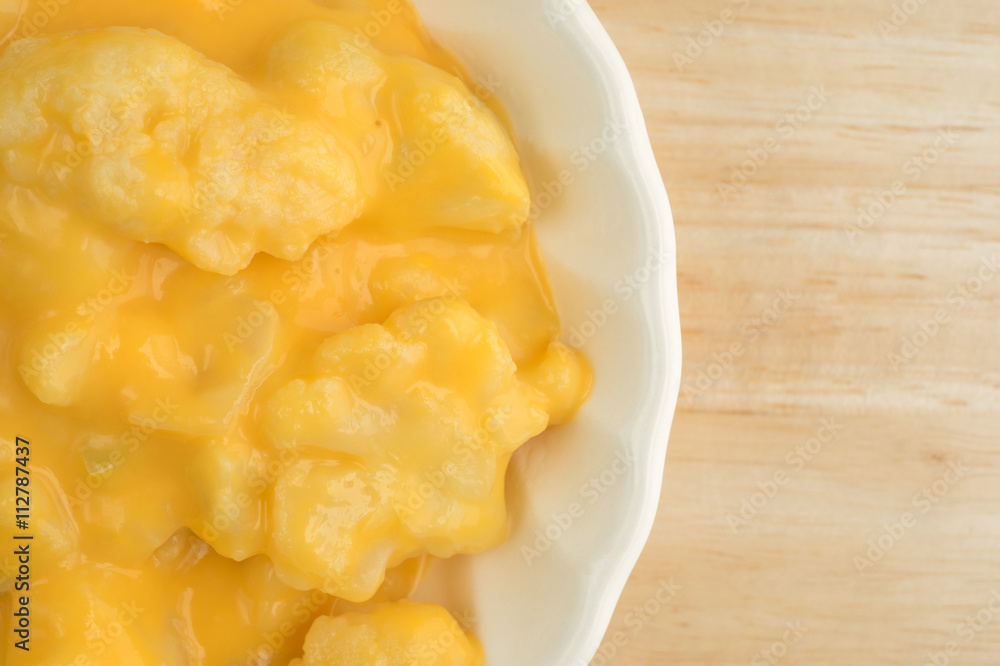 Serving of cauliflower with a cheese sauce in an old bowl top close view on table top. Serving of cauliflower with a cheese sauce in an old bowl top close view on table top.
