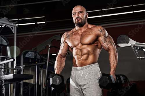 strong and handsome young man doing exercise with dumbbells