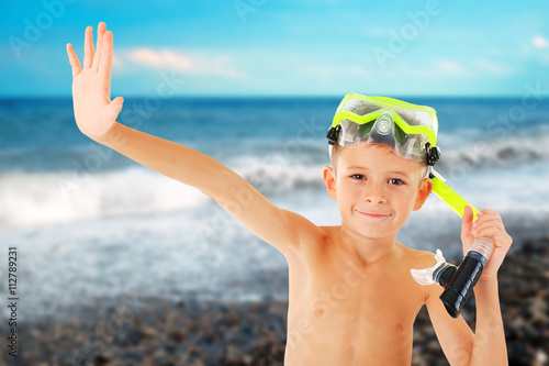 Happy boy with yellow diving mask on blurred sea background